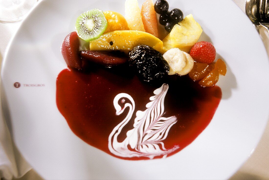 Fruit with red sauce, decorated with cream swan