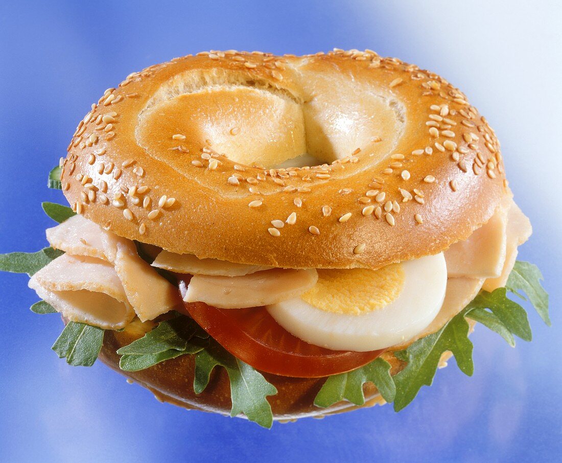 Sesame bagel with turkey breast, egg, tomato and rocket