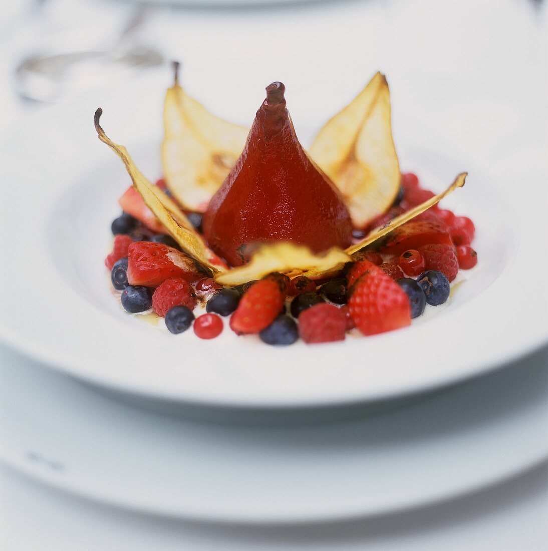 Poached red wine pear with pear crisps and berries
