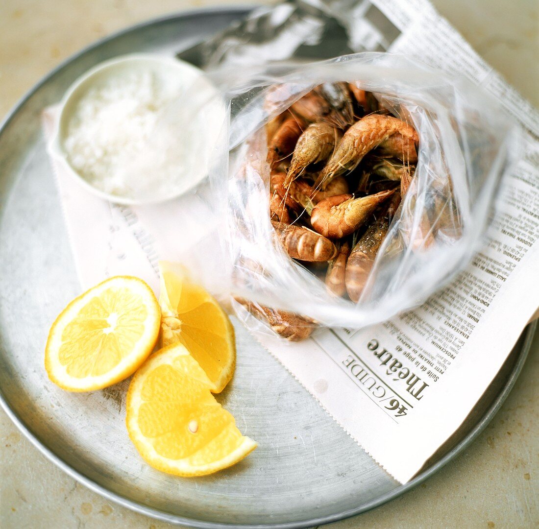 Fresh shrimps, lemons and salt on French newspaper