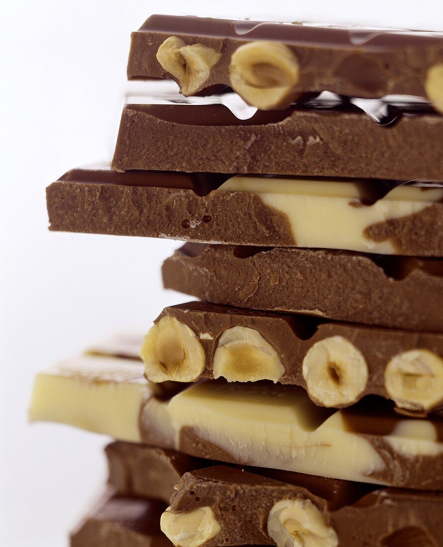 Pile of pieces of white and dark chocolate with hazelnuts