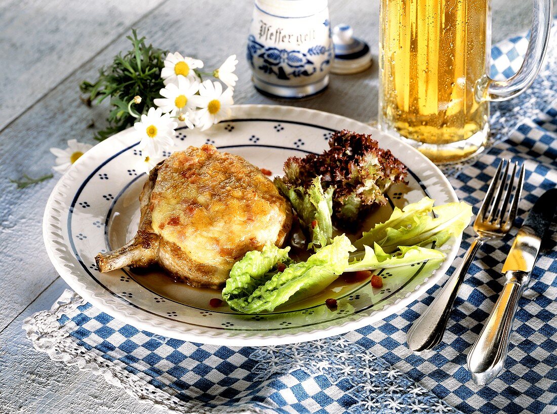 Pork chop with cheese crust and salad; beer