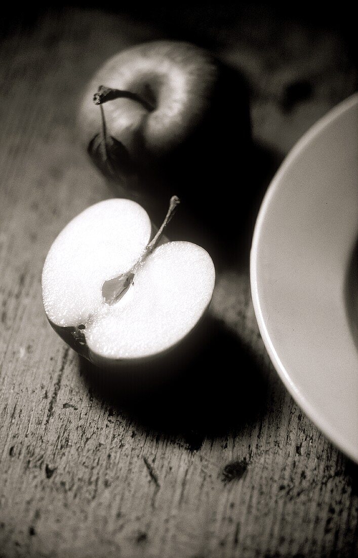 Whole and half apple beside plate