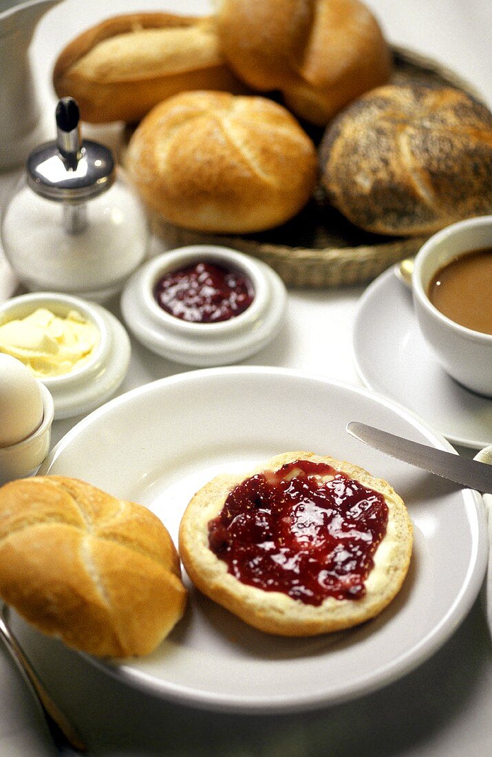 Frühstück mit Marmeladenbrötchen, Ei, Kaffee und Gebäck