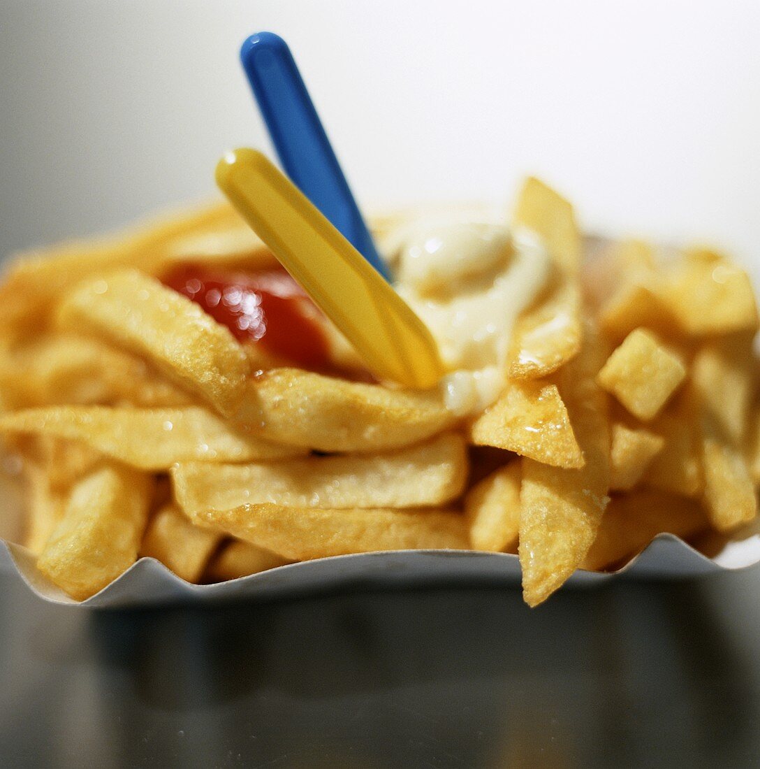 Pommes frites mit Mayonnaise, Ketchup und Plastikgabeln