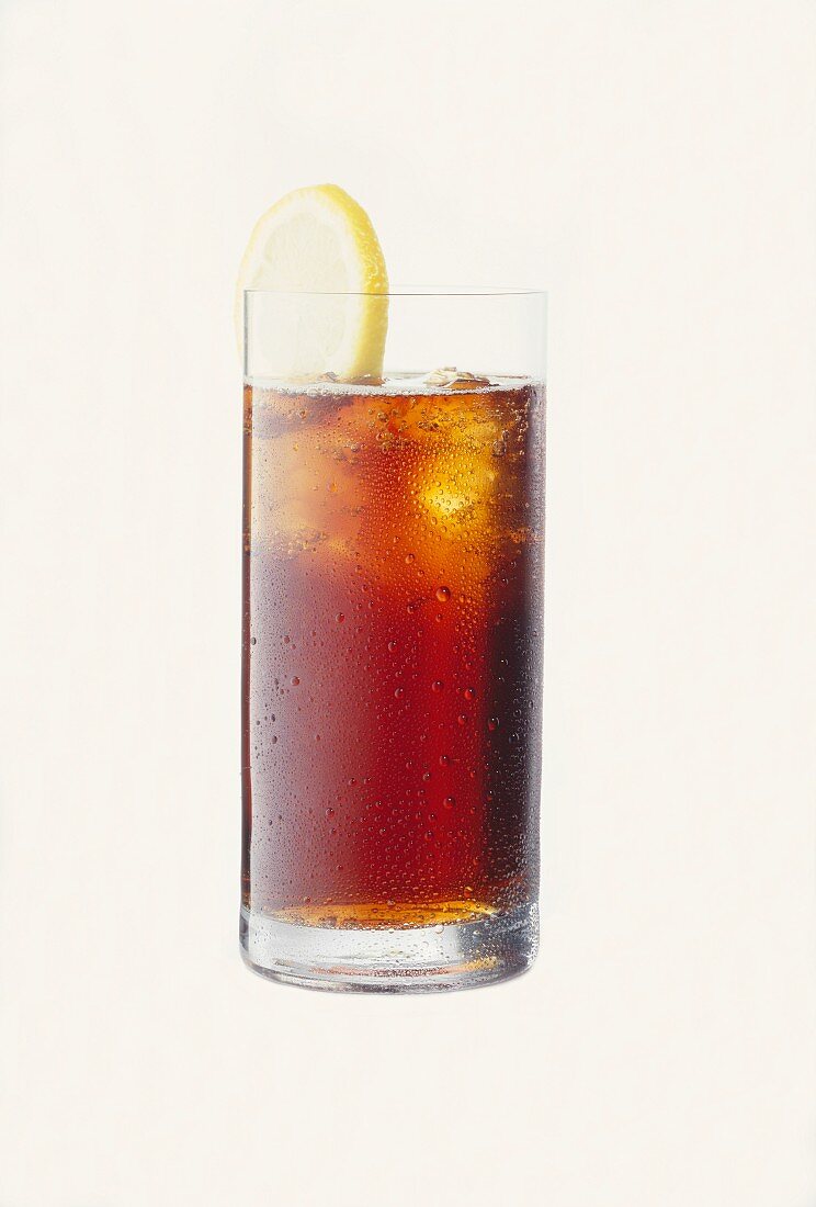 Cola im Glas mit Wasserperlen, Eiswürfeln und Zitrone