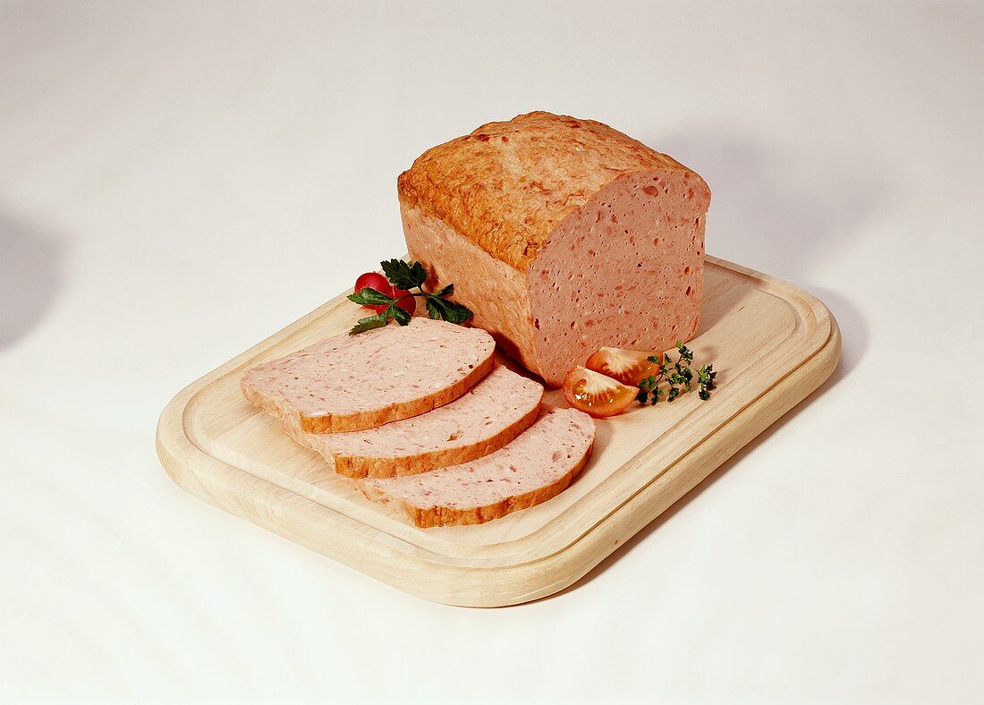Coarse meatloaf, a slice cut, on wooden chopping board