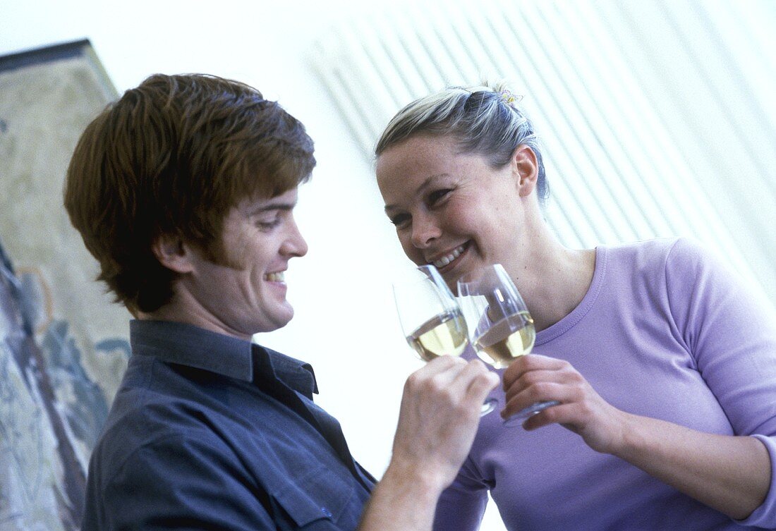 Young couple chinking white wine glasses