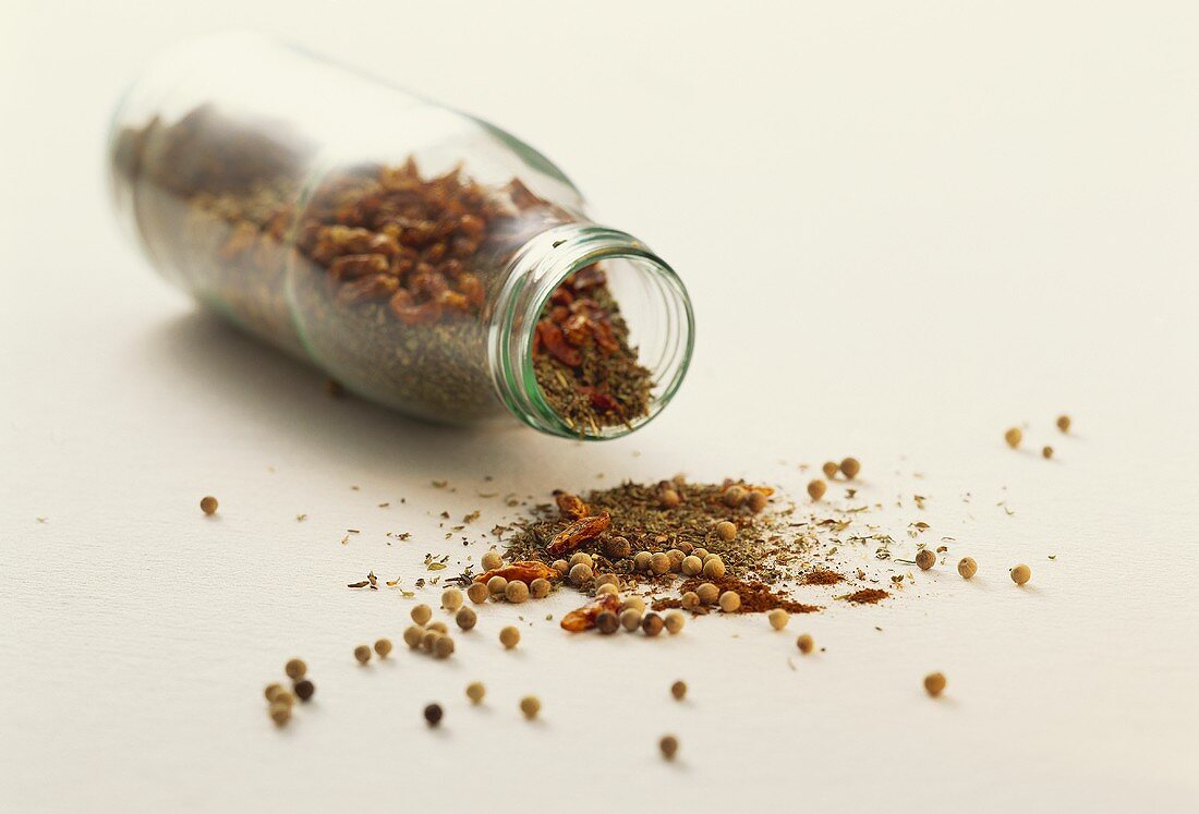 Assorted spices in front of an inside horizontal glass bottle