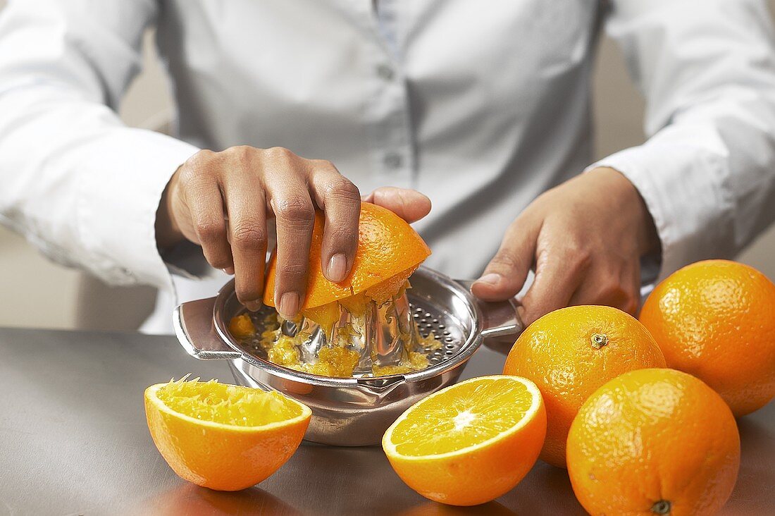 Hände pressen Orangen aus