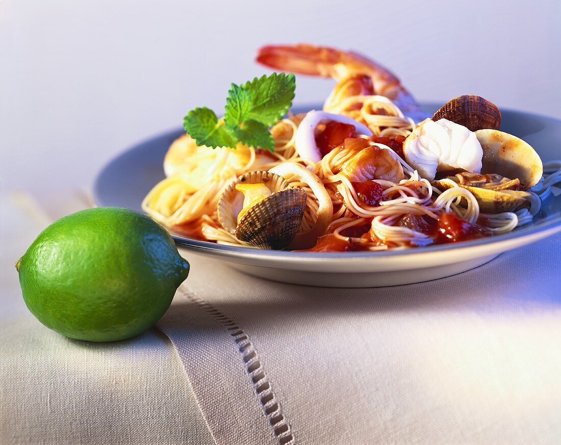 Spaghetti with seafood and tomatoes; lime