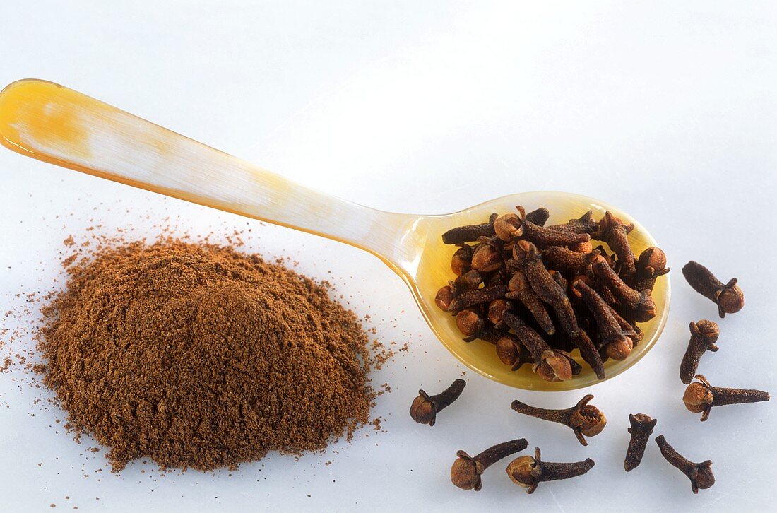 Cloves on spoon and ground cloves