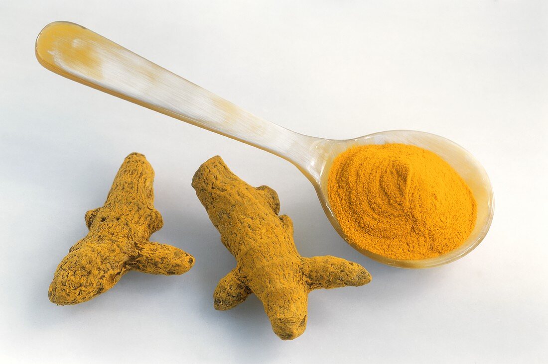 Turmeric roots and a spoonful of ground turmeric