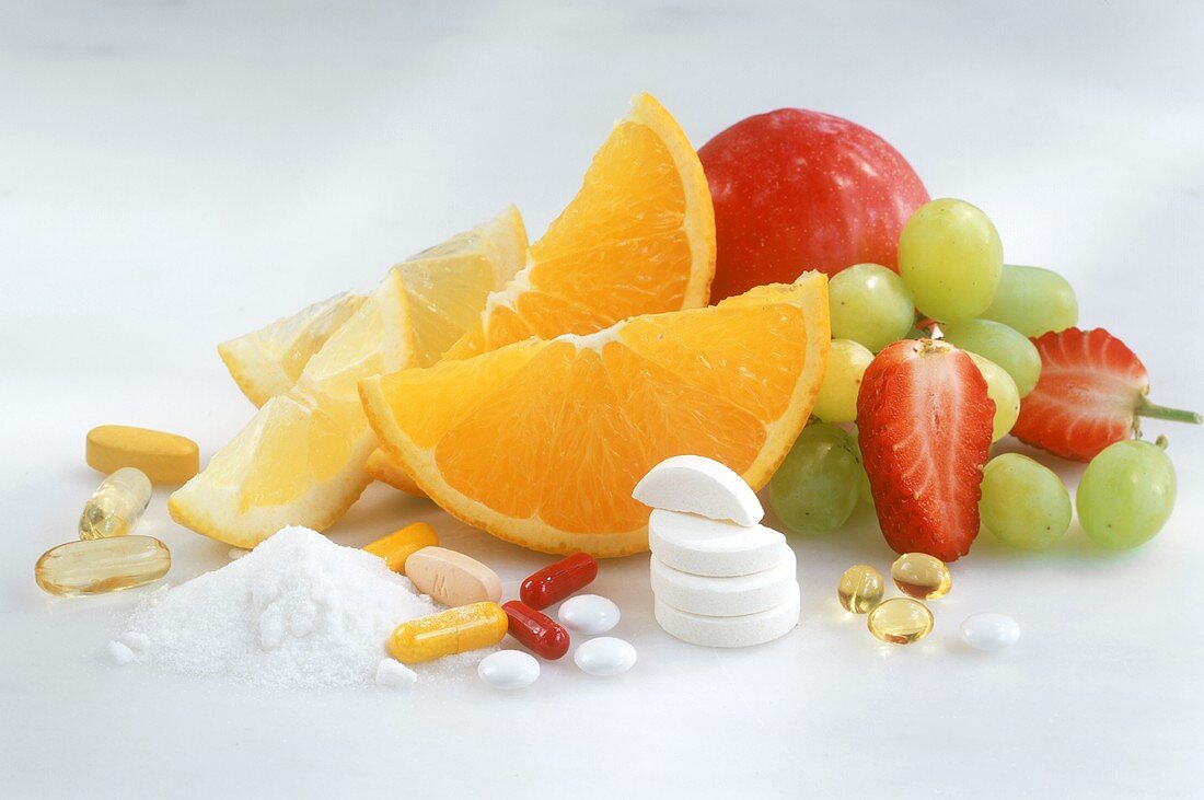 Frisches Obst, Vitamintabletten und Vitaminpulver