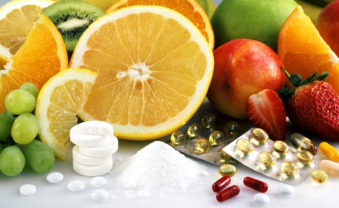 Frisches Obst, Vitamintabletten und Vitaminpulver