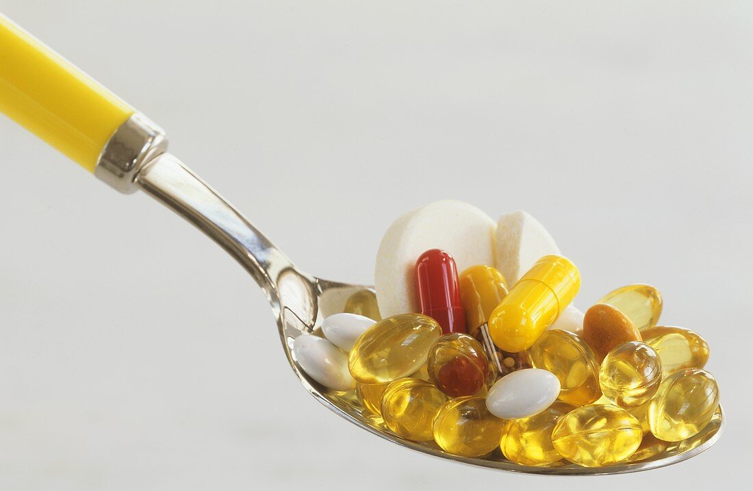 Verschiedene Vitamintabletten auf Löffel