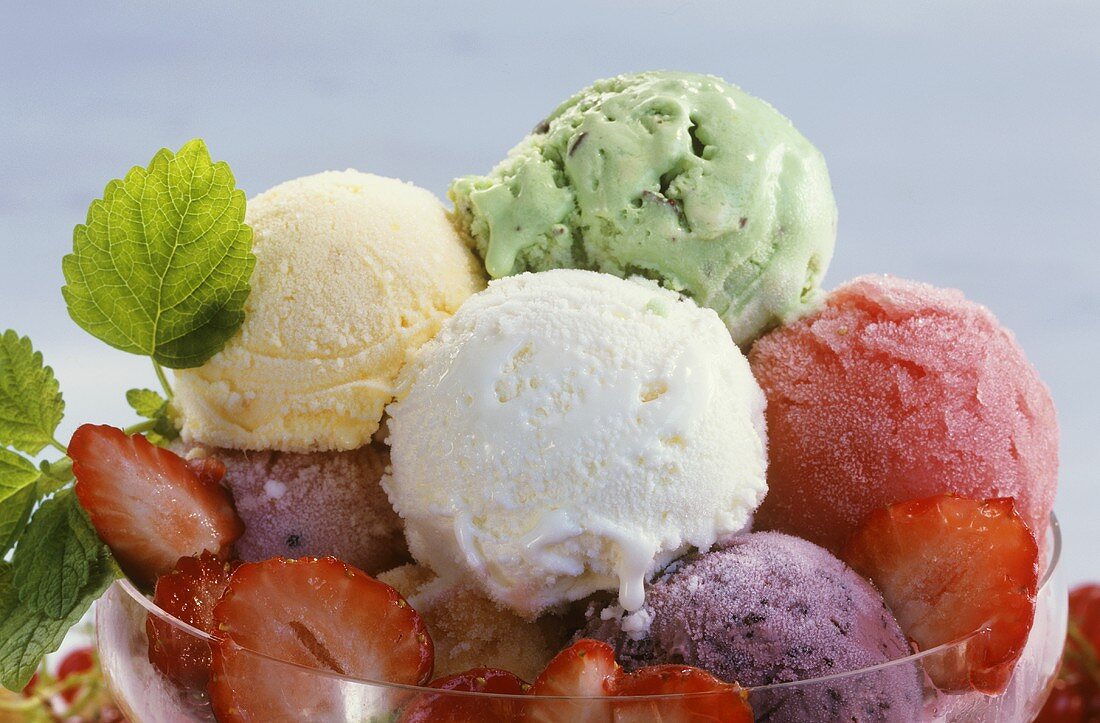 Assorted ice creams with strawberries and lemon balm