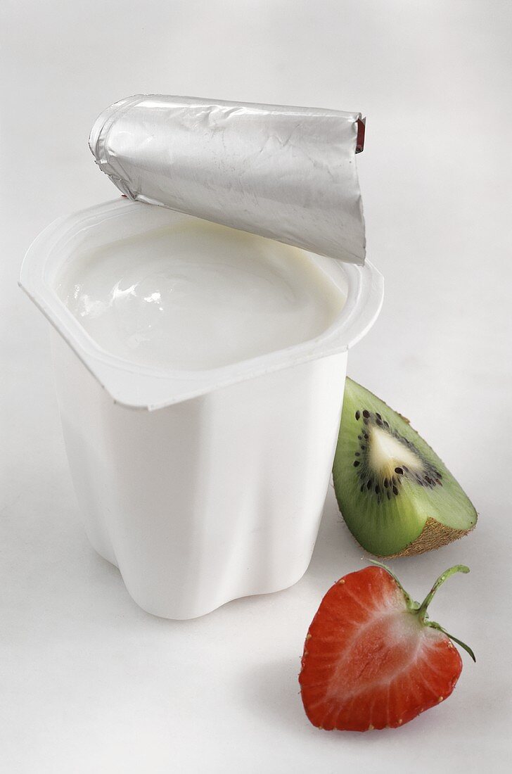 A pot of yoghurt, fresh strawberry and kiwi fruit