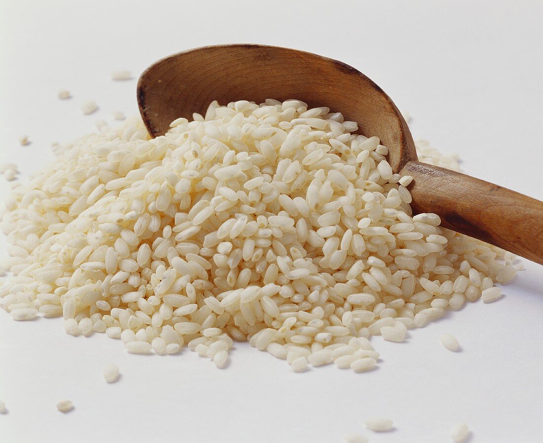 A heap of Arborio rice with wooden spoon