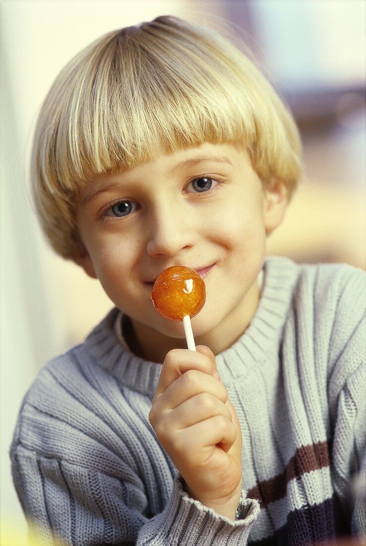 Small boy licking lollipop