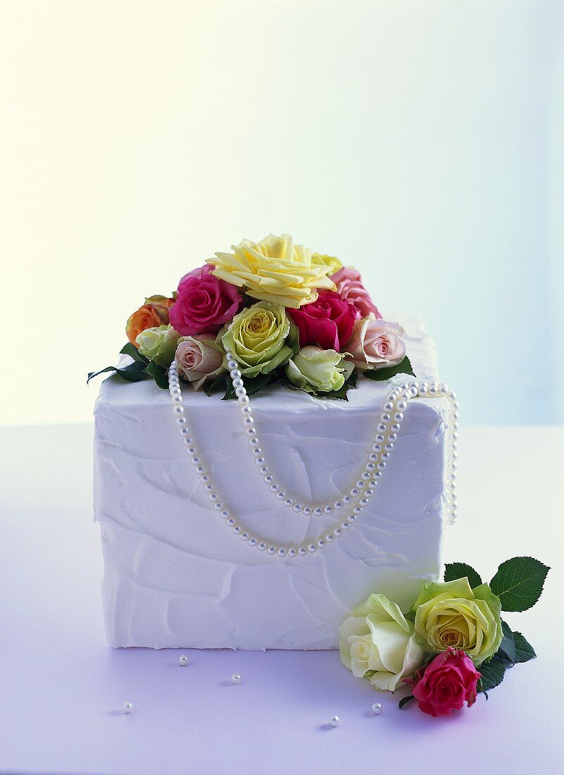 weiße Hochzeitstorte mit Rosen und Perlenkette