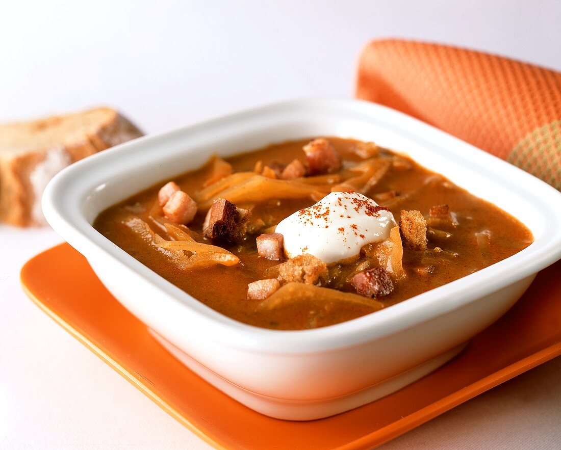 Spicy white cabbage soup with bacon and sour cream