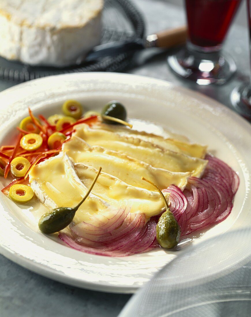 Slices of warm Camembert with onions, olives and capers