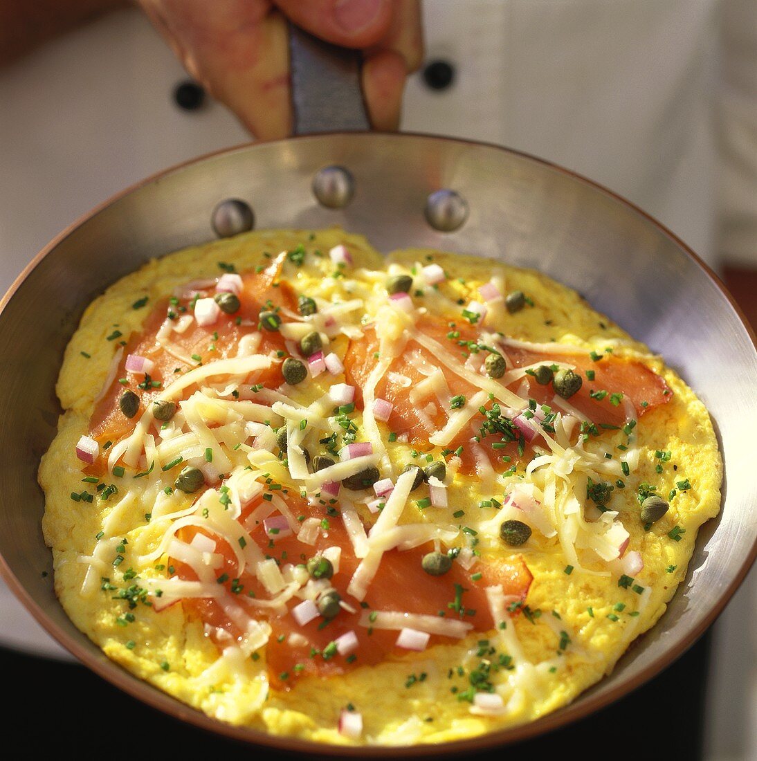 Hand holding pan with salmon frittata