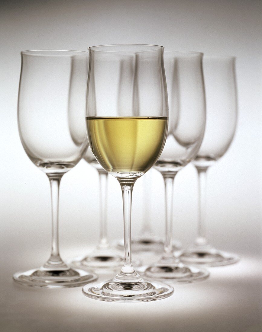 Glass of white wine in front of empty white wine glasses