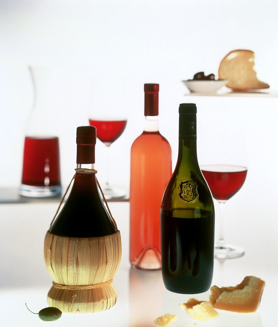 Rotweinflaschen und -gläser, Roseflasche, Käse und Oliven