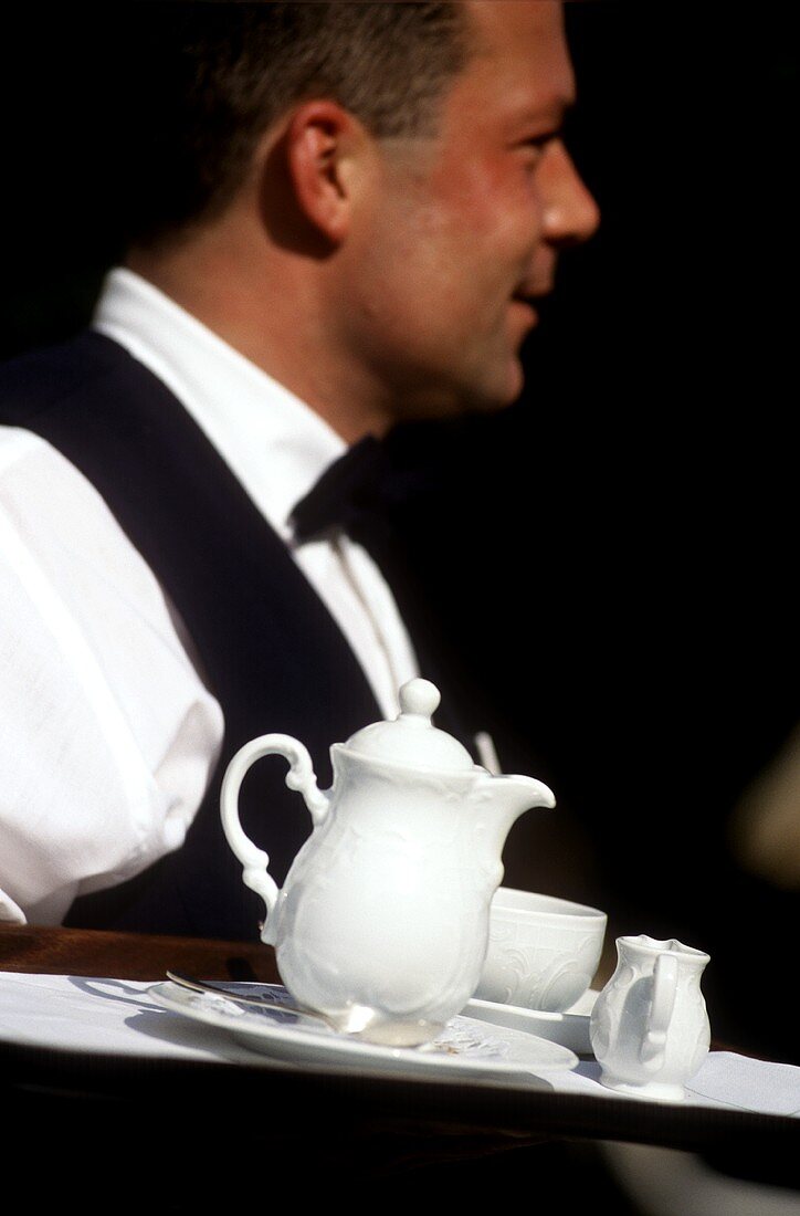 Waiter serving tray of coffee and milk