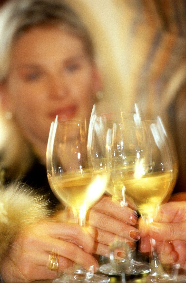 Elegant people clinking white wine glasses
