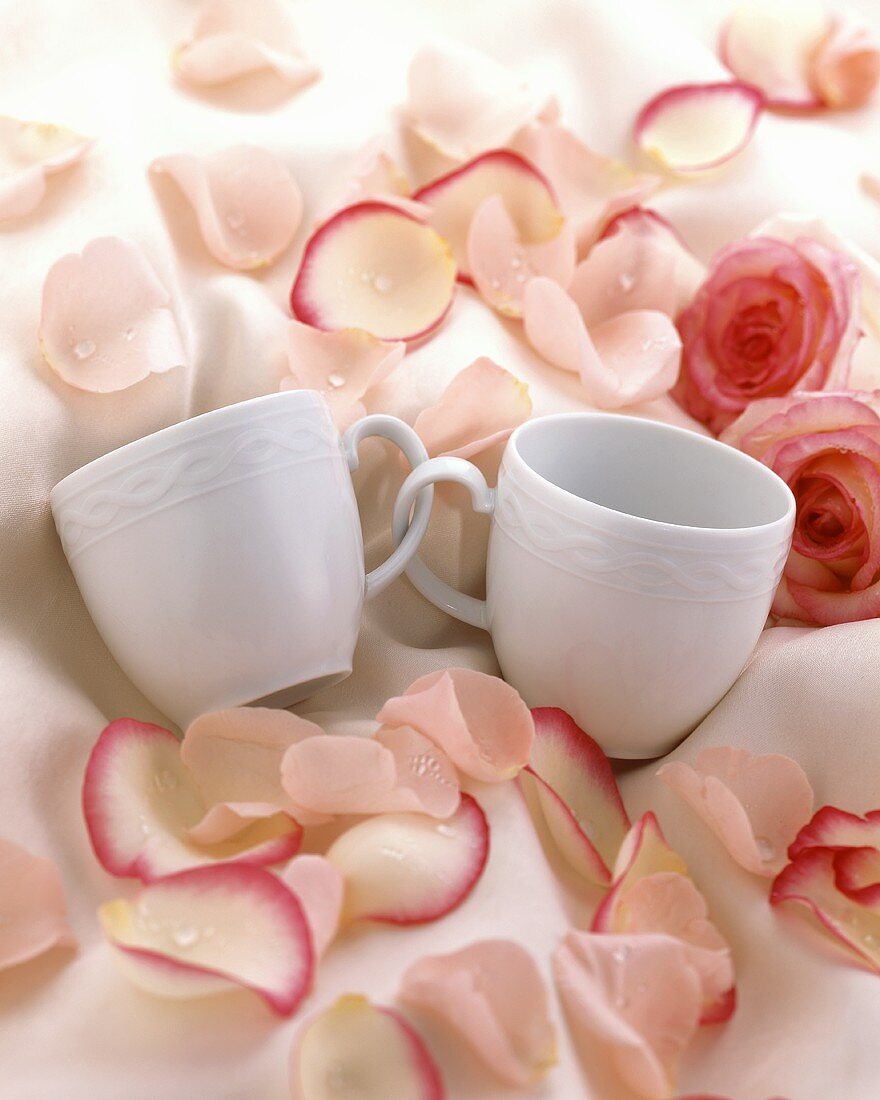 Cups with handles entwined, with rose petals