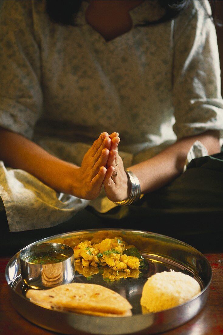 Inderin betet vor Tablett mit Speisen