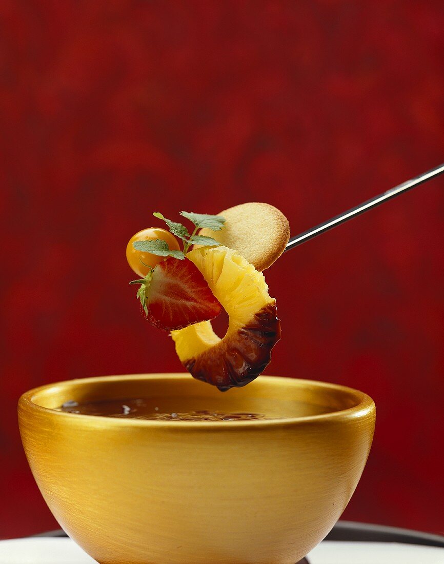 Chocolate fondue with fruit on fondue fork