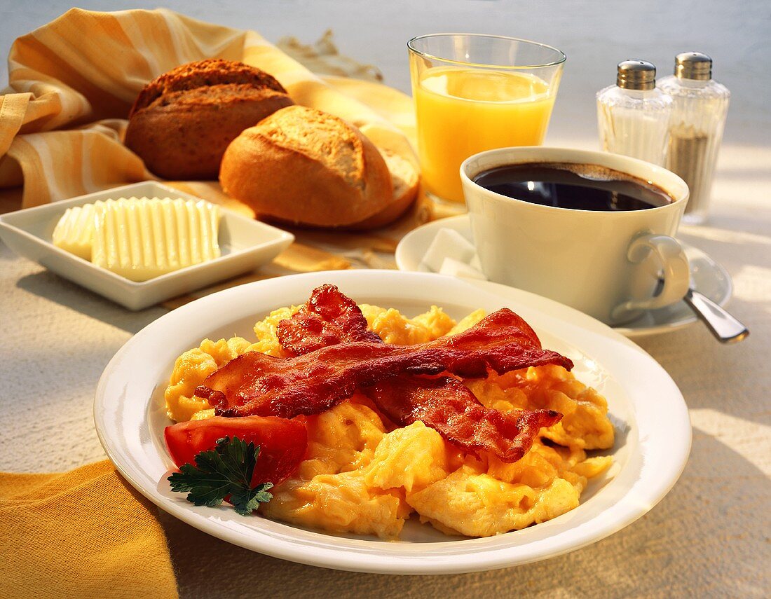 Frühstück mit Rührei und Speck, Kaffee, Orangensaft, Brötchen