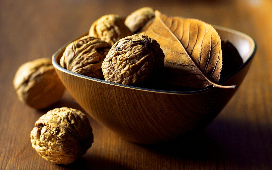 Walnuts in brown bowl with leaf