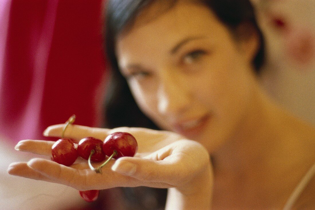 Junge Frau hält rote Kirschen in der Hand