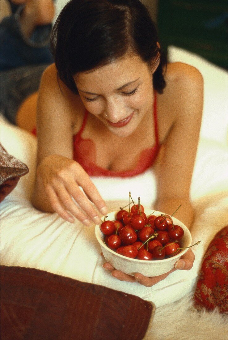 Young woman holding bowl of red cherries