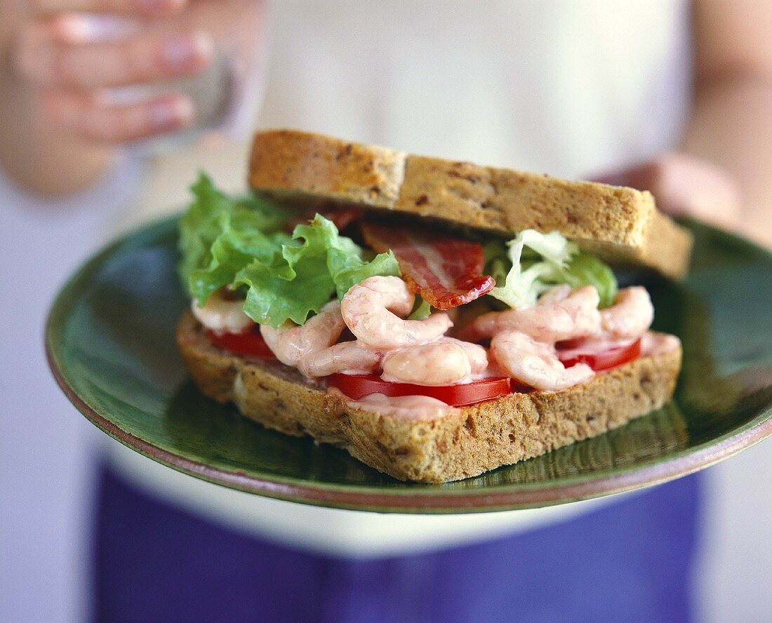 Shrimps, bacon, tomatoes and cocktail sauce in a sandwich