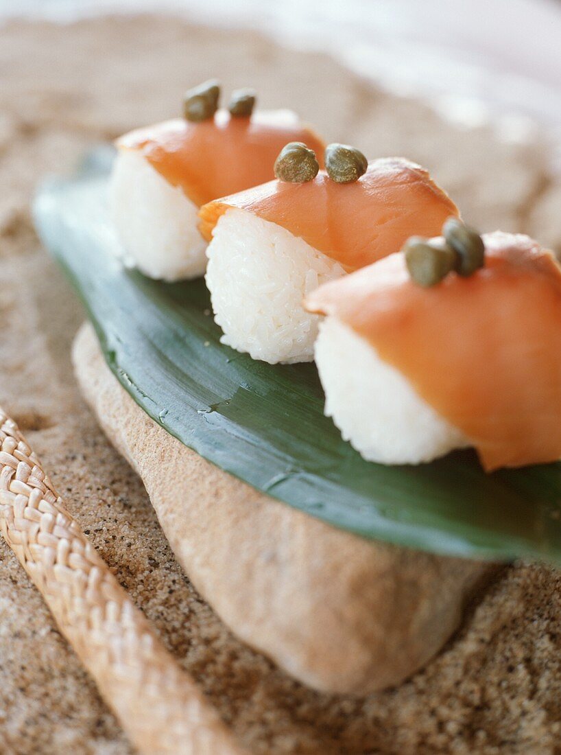 Sushi mit Lachs und Kapern auf Bananenblatt