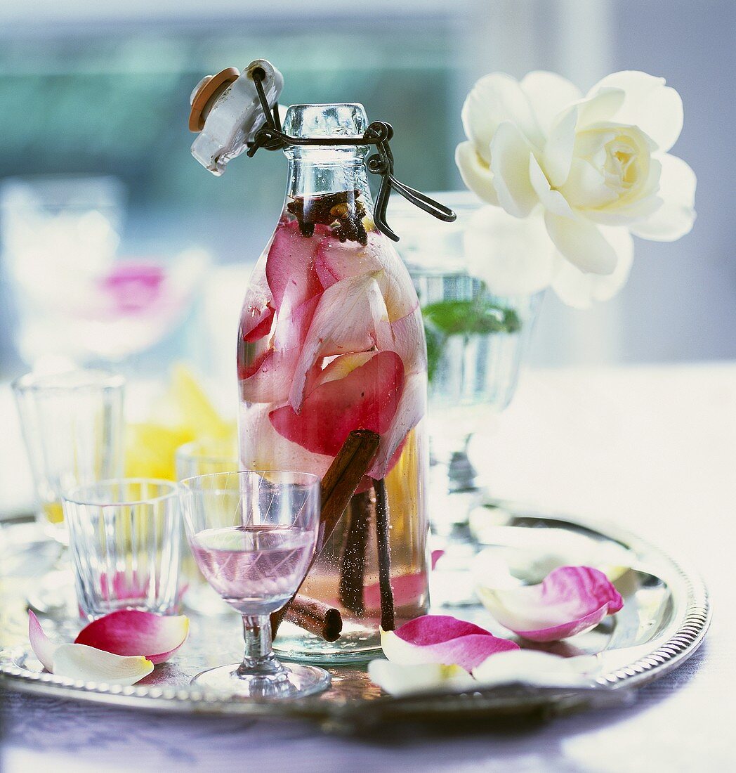 Rosenwasser in Flasche und Glas auf Tablett