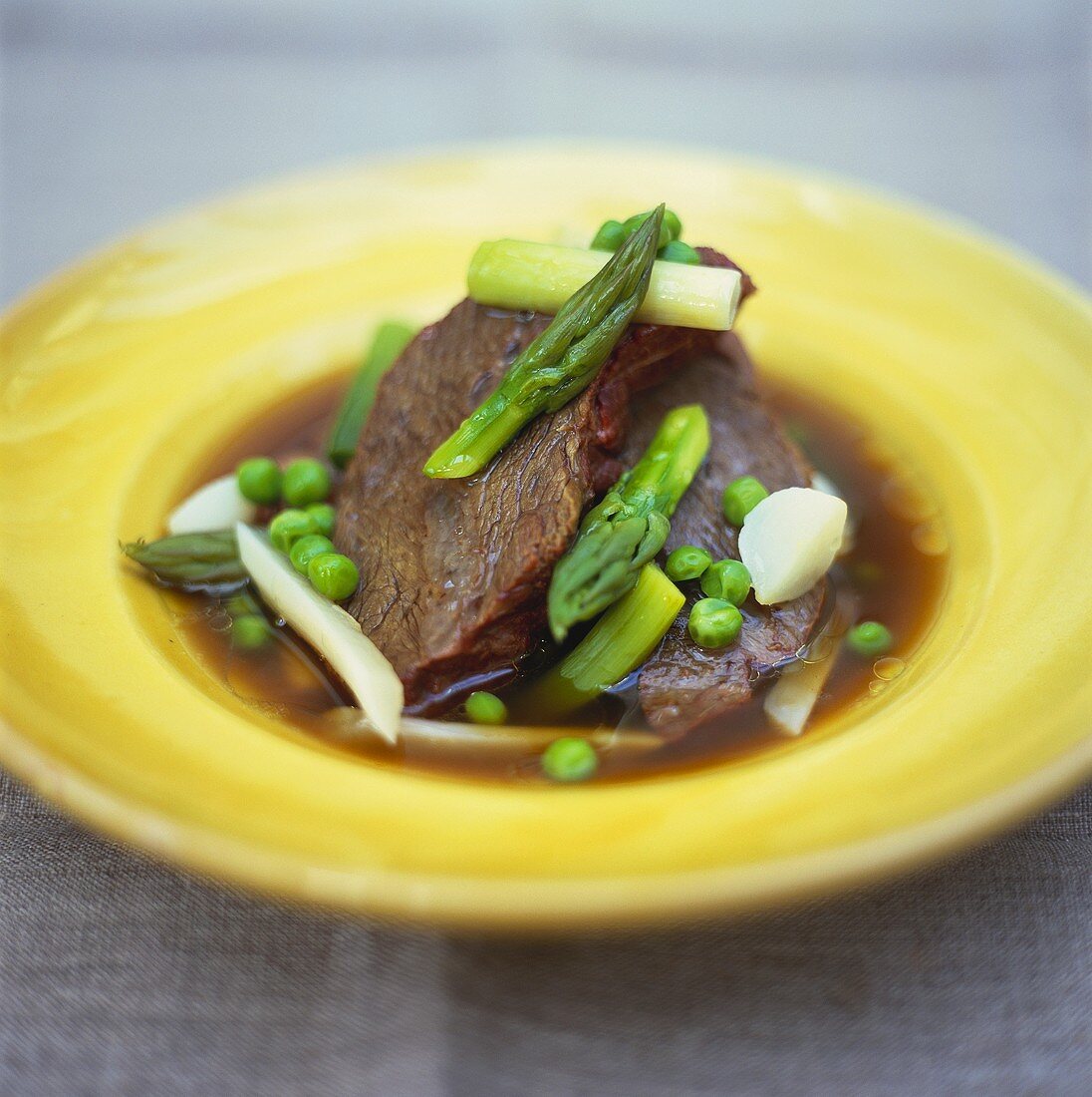 Broth with beef, green asparagus and peas