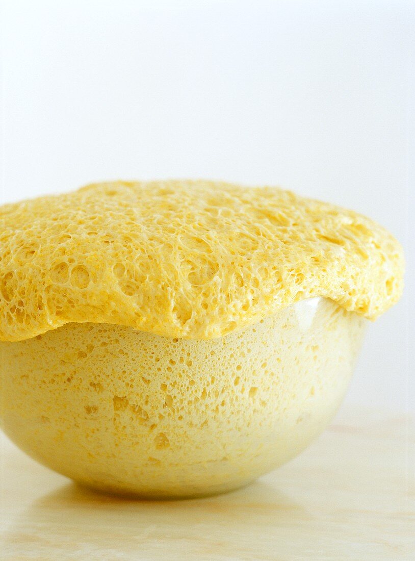 Risen yeast dough in a glass bowl