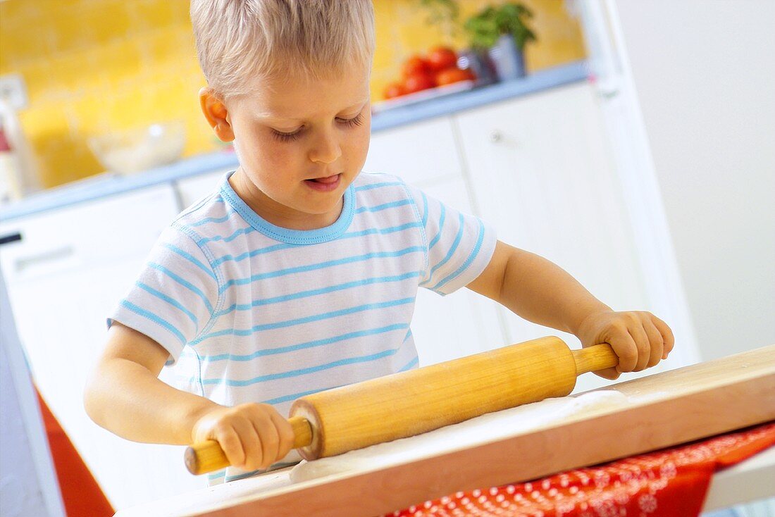 Small boy rolling out pizza dough