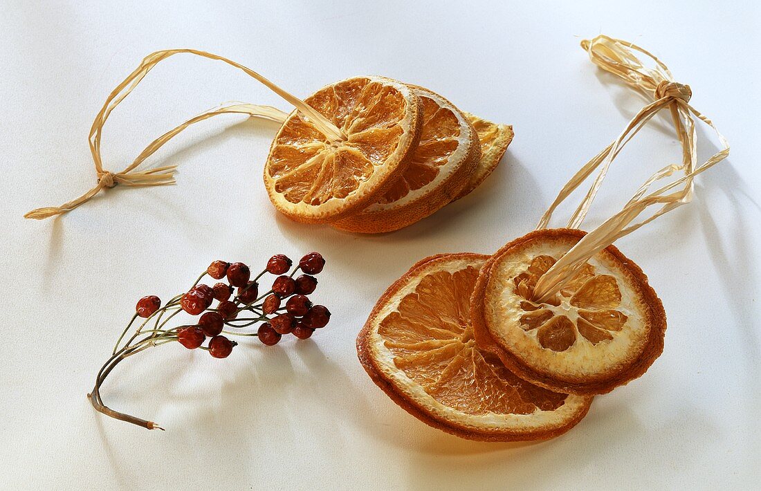 Getrocknete Orangenscheiben auf Bast; getrocknete Hagebutten