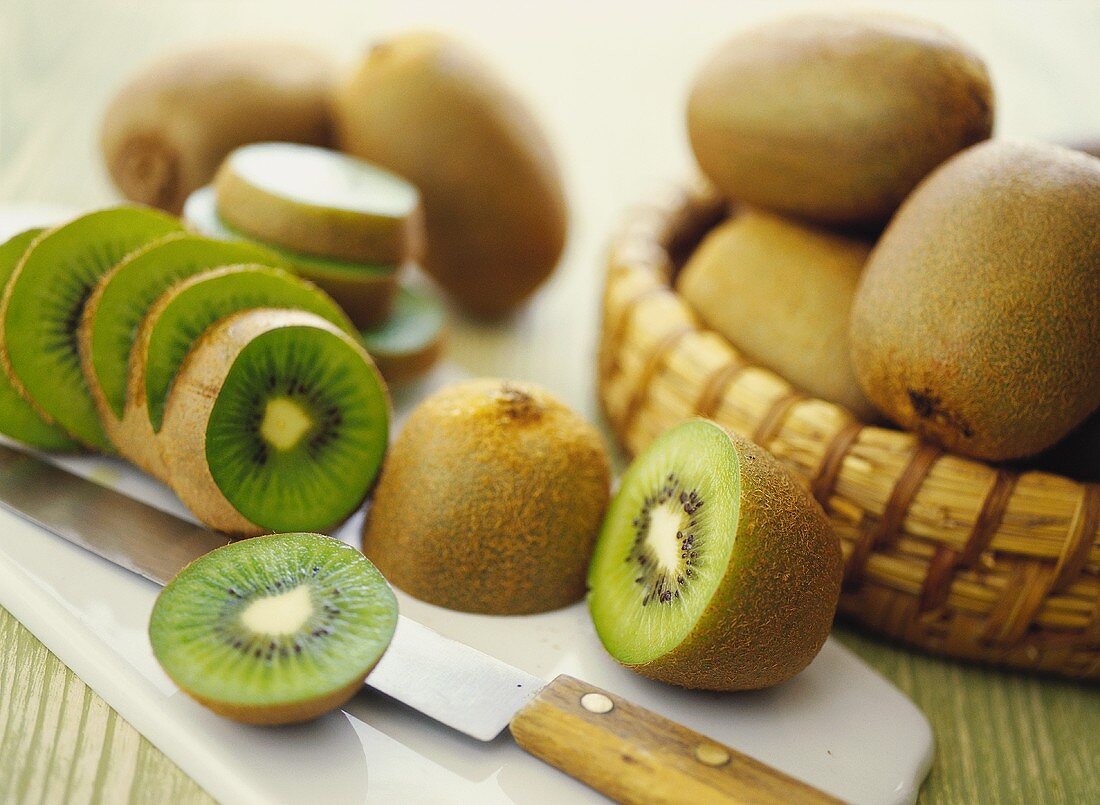 Fresh kiwi fruits in basket and on chopping board