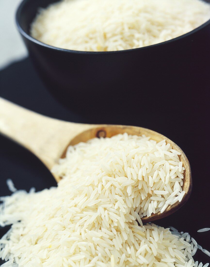 Basmati rice on wooden spoon in front of rice bowl