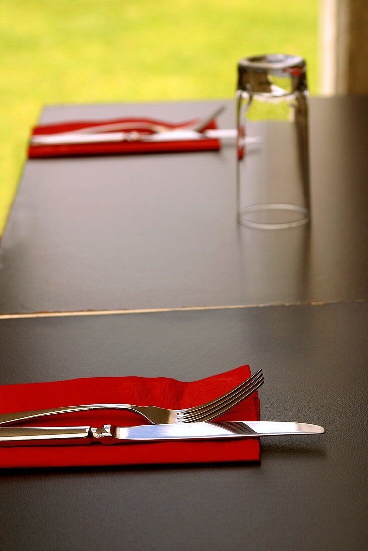 Table laid simply, with cutlery and red napkins