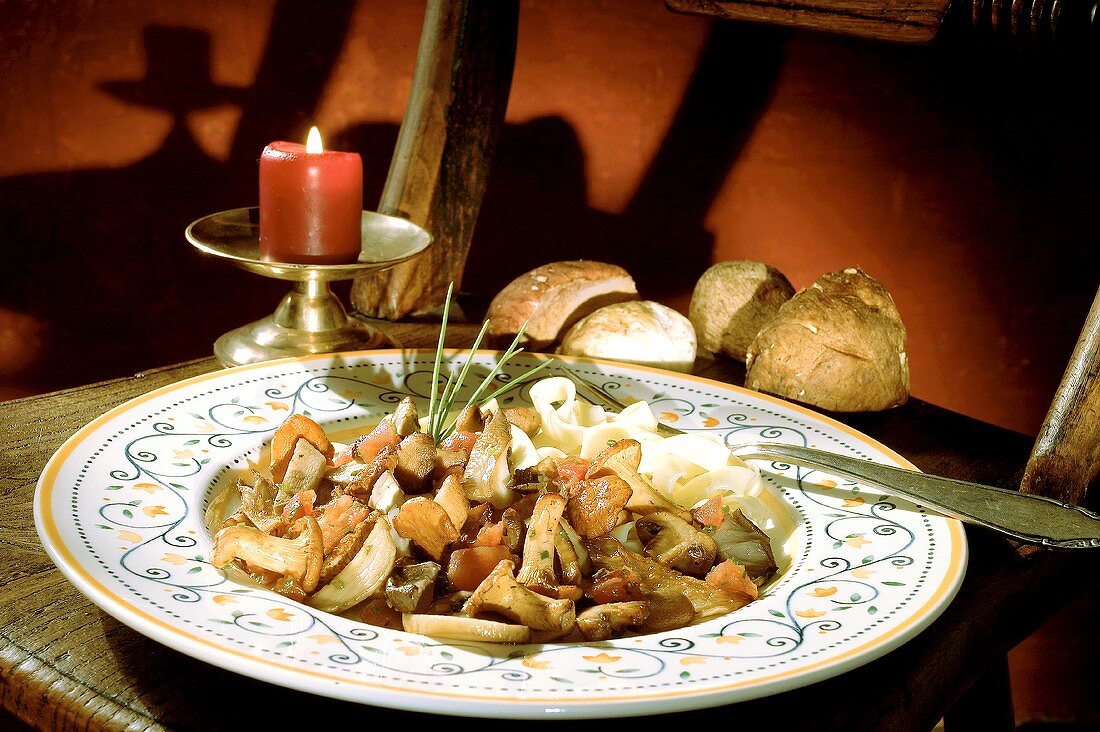 Pilzragout mit Tomaten und Bandnudeln; Brot; Kerze